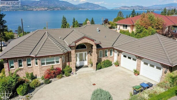 A two-story house with a garage, a driveway, and a view of a lake and mountains. - New 3BR Guest Suite |  Lakeview,  Private Entry (Kelowna)
