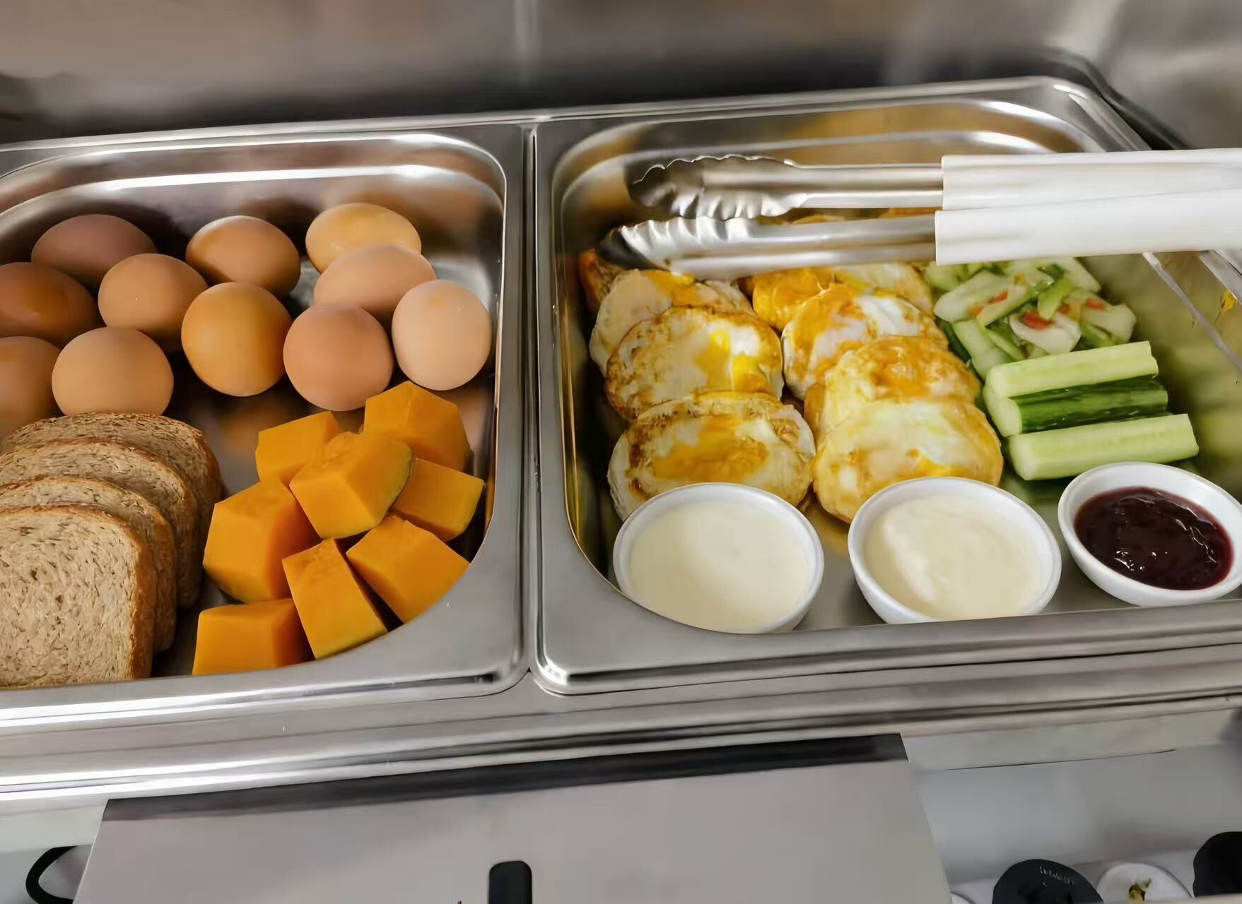 A breakfast buffet with eggs, cheese, bread, and various side dishes.