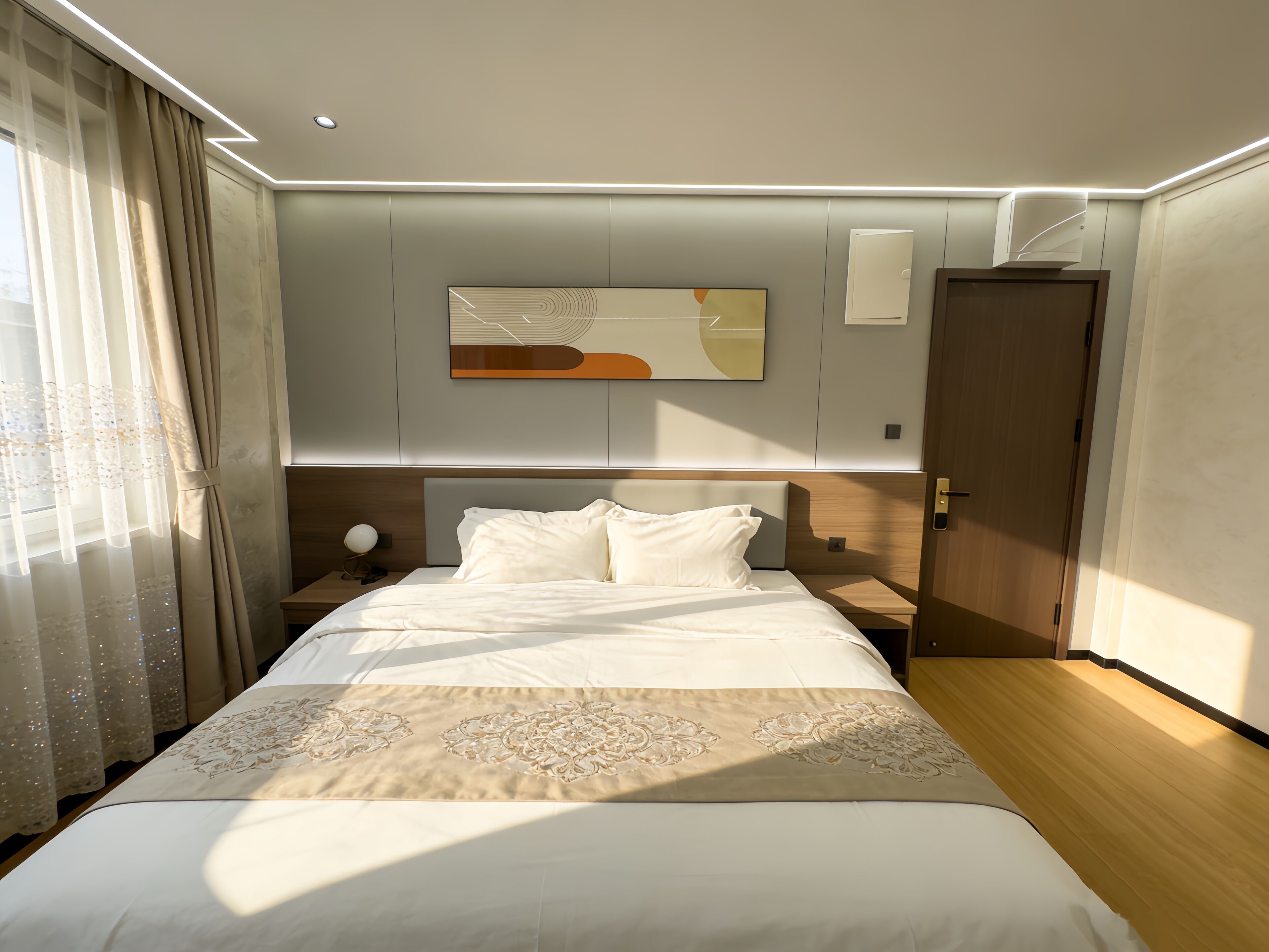 A modern hotel room with a large bed, a bedside table, a lamp, and a painting on the wall.