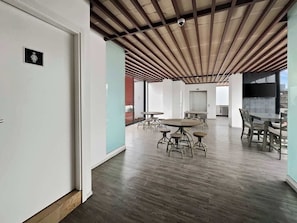 Ein offener Arbeitsbereich mit hoher Decke, Holzbalken und einem runden Tisch in der Mitte mit Stühlen.