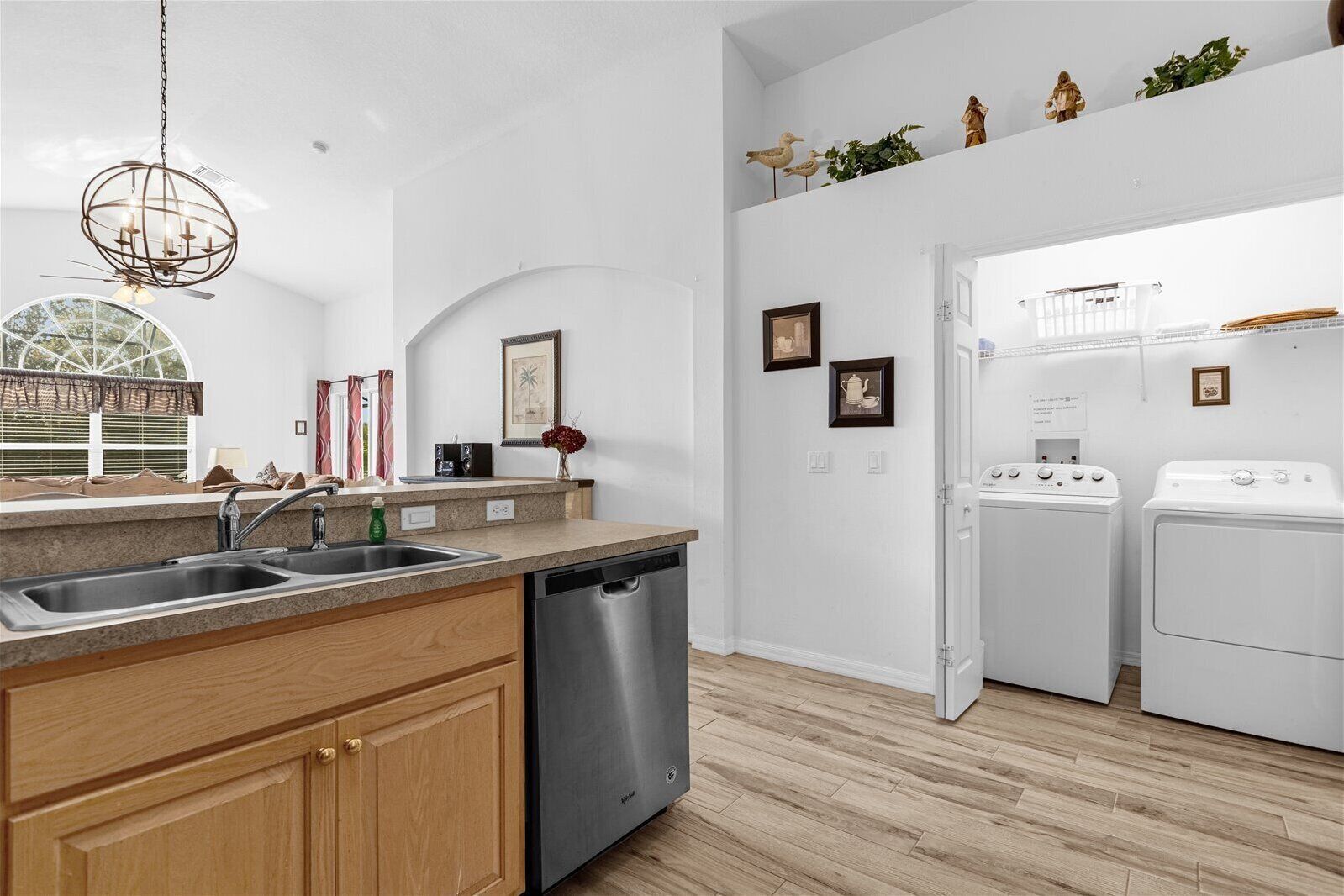 A modern kitchen with a dishwasher, double sink, and a hanging light fixture.