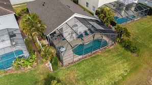 Ein Wohnhaus mit Swimmingpool, überdachter Terrasse und umgebender Bepflanzung.