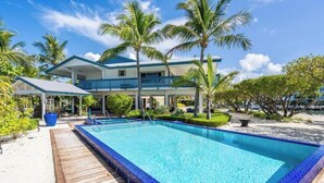 Een resort met een zwembad, palmbomen en een gebouw met twee verdiepingen.