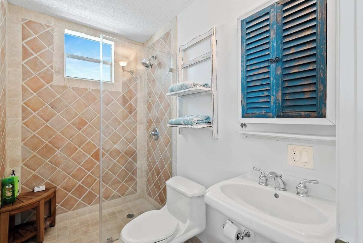 Une salle de bain équipée d’une douche, de toilettes, d’un lavabo et d’une fenêtre.