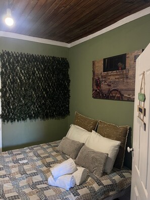 Ein Zimmer mit einem Bett, einer Wand mit Dekoration, einem gerahmten Bild und einer Tür.