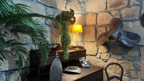 A stone wall, a lamp, a hat, a plant, and a desk with a telephone.