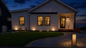 Et toetagers hus med en veloplyst veranda, en synlig garageport og en belagt indkørsel.