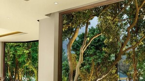 A restaurant with tables set for dining, large windows with a view of trees, and a modern interior design. - Ayu Hotels  (Ukhimath)