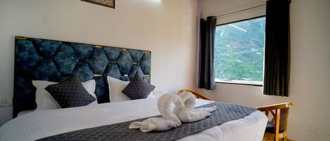 A bed with a quilted headboard, a window with curtains, and a wooden chair.