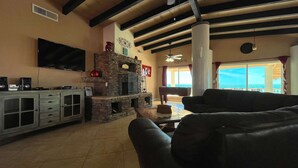 Olohuone, jossa on kivinen takka, litteänäyttöinen televisio, biljardipöytä ja suuri ikkuna, josta on kaunis näköala.