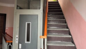 Een trap met een leuning, een deur met een raam en een metalen hekwerk.