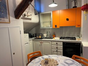 A compact kitchen with a dining table, chairs, a refrigerator, a stove, and a sink. - Casa Lara Milano - One Bedroom Apartment, Sleeps 3 (Milano)