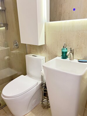 Et badeværelse med toilet, håndvask og bruser.