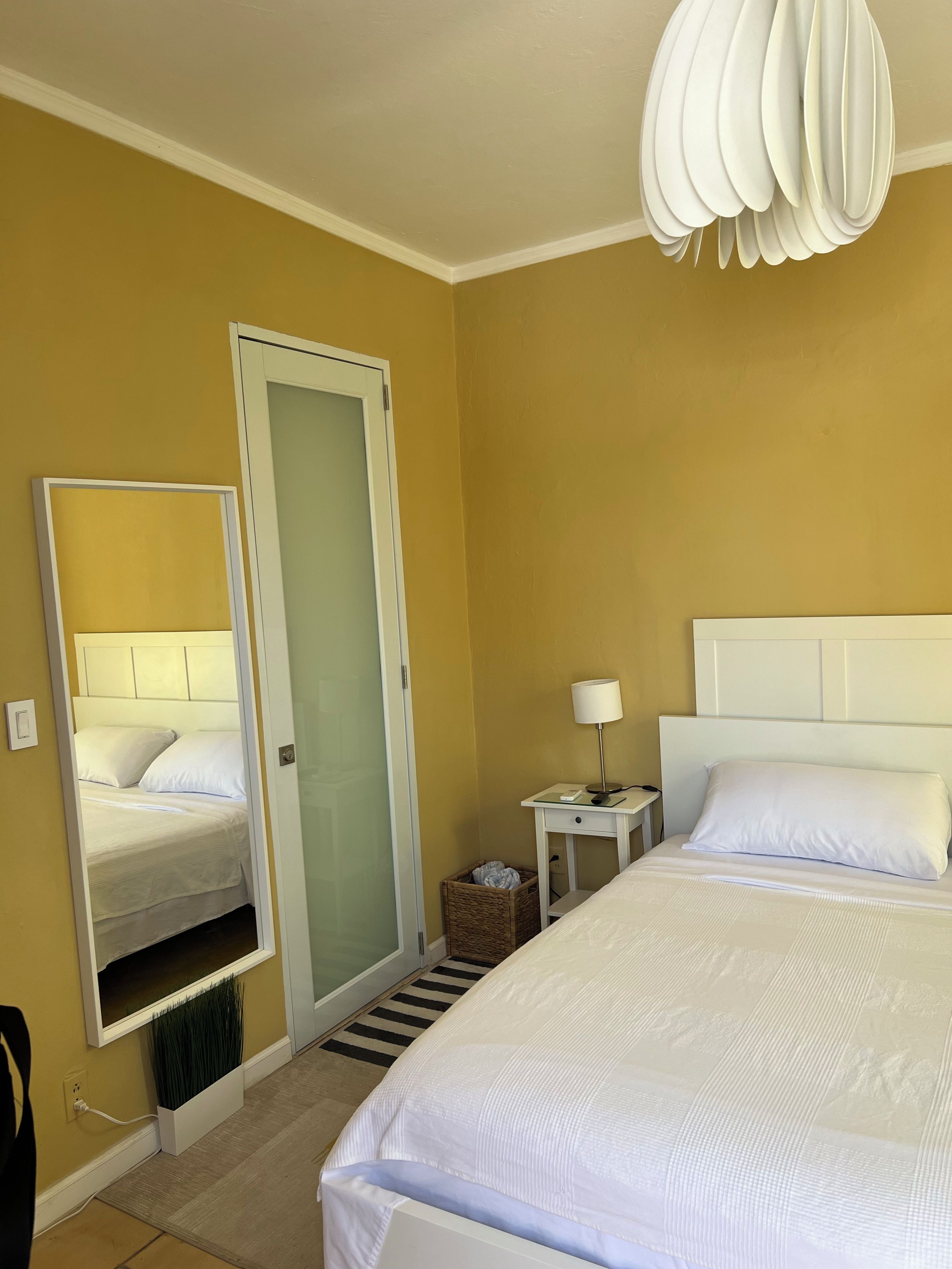 Ein Hotelzimmer mit einem Bett, einem Nachttisch, einer Lampe und einem Spiegel.
