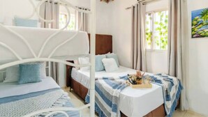 Ein Zimmer mit Etagenbetten, einem Nachttisch mit Ablage und einem Fenster mit Vorhängen.