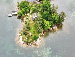 Vue aérienne d’une petite île avec une maison, un quai et un bateau.