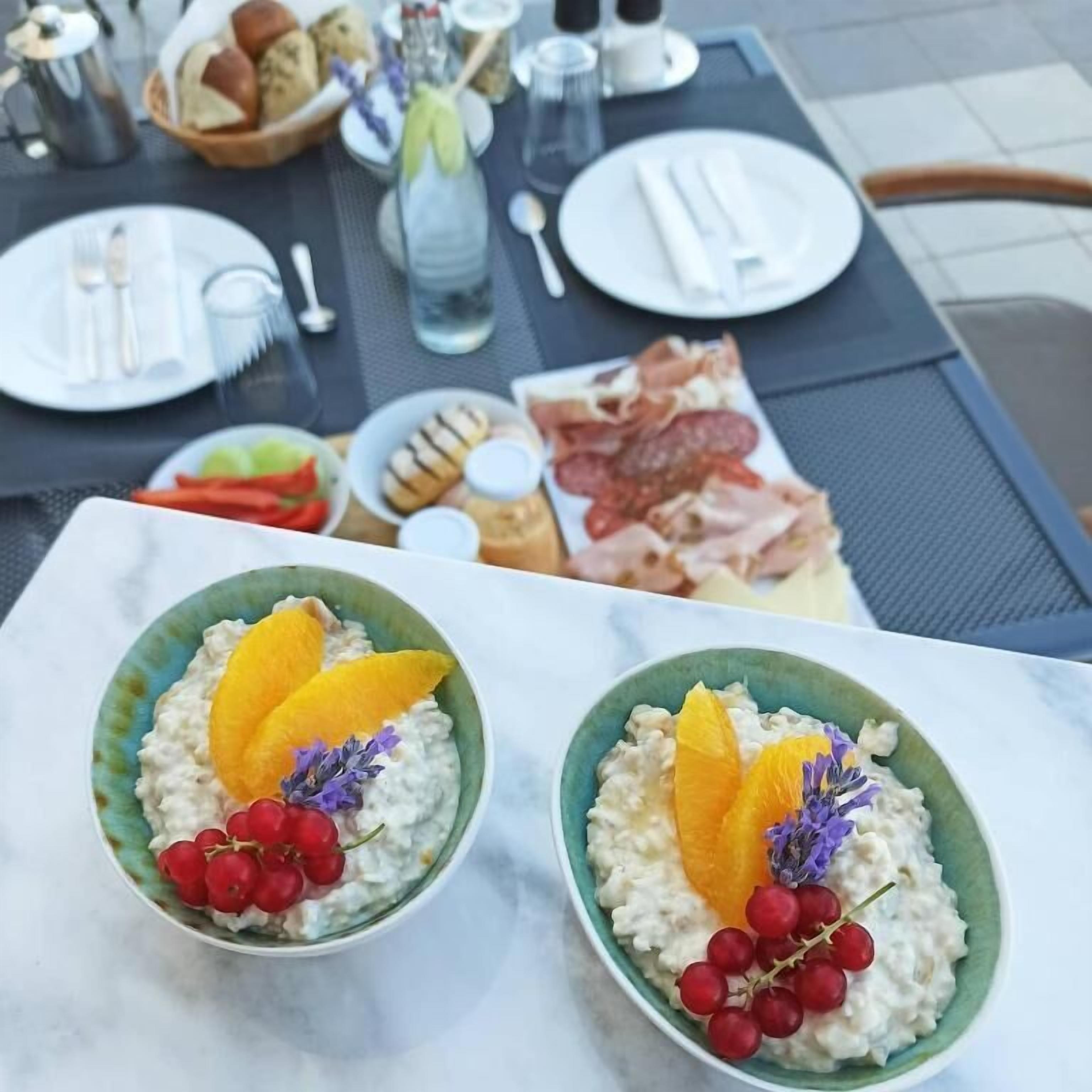 Deux bols de porridge aux fruits, posés sur une table où se trouvent également des assiettes de nourriture et des couverts.