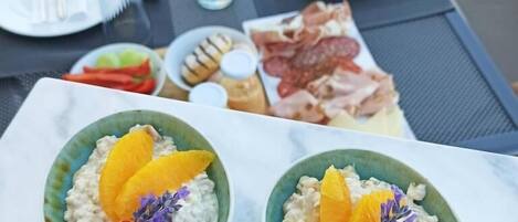 Deux bols de porridge aux fruits, posés sur une table où se trouvent également des assiettes de nourriture et des couverts.