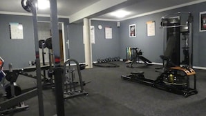 Un gimnasio con equipo de levantamiento de pesas, barra de dominadas y banco.