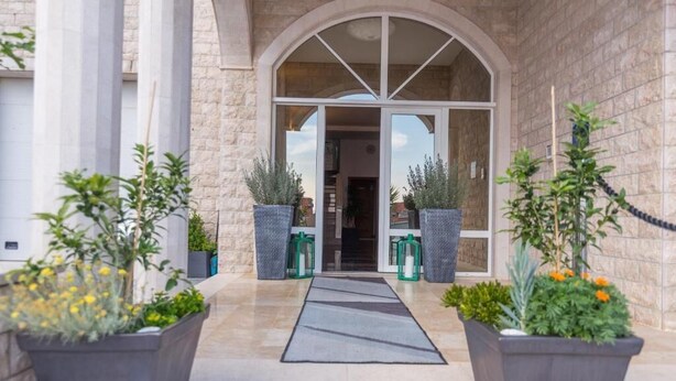 Fachada de piedra con un amplio arco de entrada y macetas con plantas.