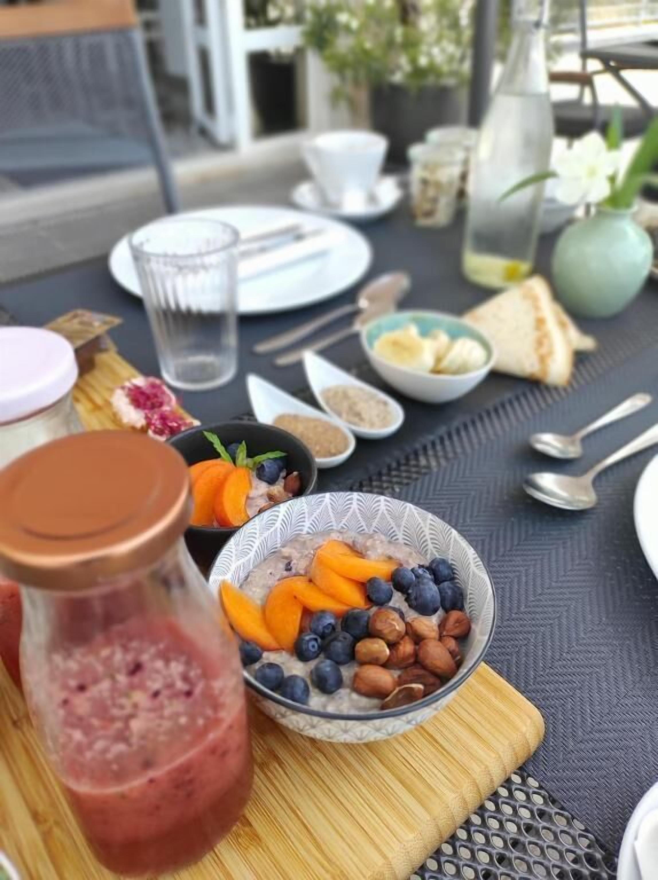 A breakfast table with a bowl of oatmeal, a glass of water, and a bottle of juice.