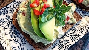 Un plato con tostada de aguacate sobre un plato de cerámica estampado.