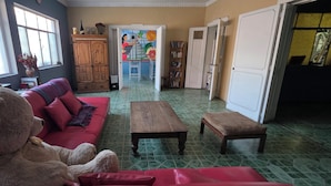 A living room with a sofa, a large teddy bear, a wooden table, and a bookshelf.