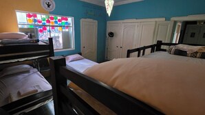 A room with bunk beds, a window with colorful decorations, and white doors.