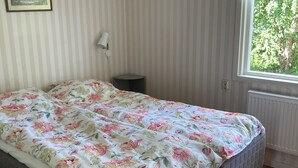 Ein Schlafzimmer mit einem Bett, einer Nachttischlampe, einem Fenster und einer Heizung.