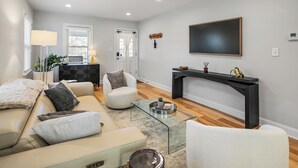 Un salon moderne comprenant un canapé, un fauteuil, une table basse, une cheminée et un téléviseur à écran plat fixé au mur.