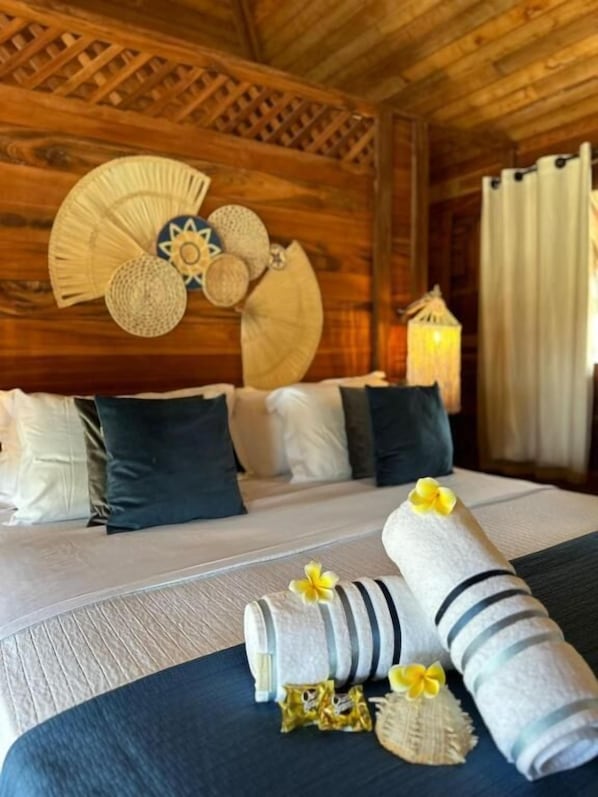 Een houten kamer met een bed, kussens, een ventilator en een lamp.
