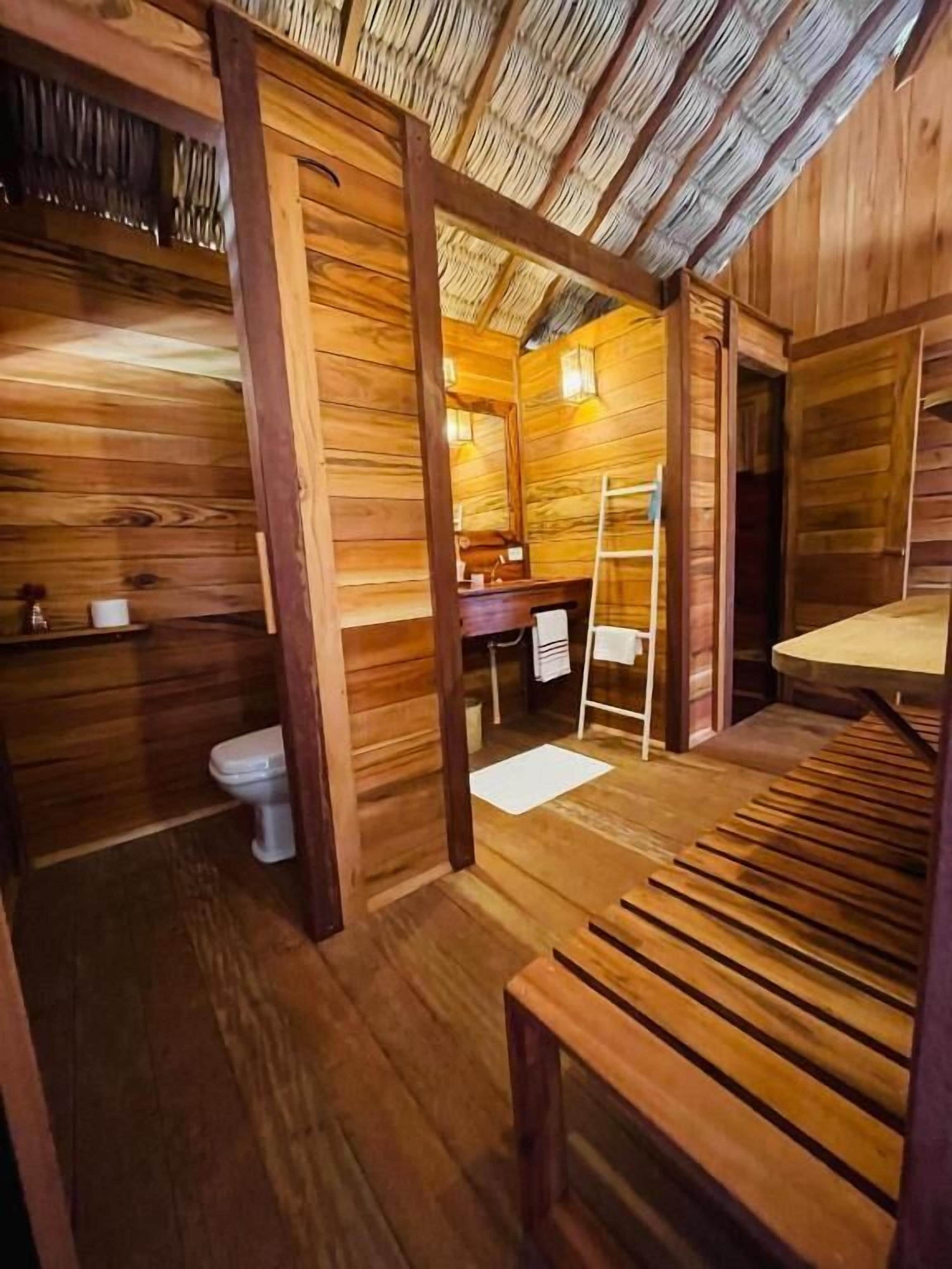 Ein Holzhütten-Innenraum mit einer hölzernen Bank, einer Toilette und einem kleinen Tisch.