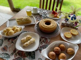 Una mesa con diferentes productos de repostería, un vaso de bebida y un mantel con estampado floral.