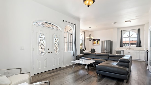 Una sala moderna con un sofá modular, una mesa de centro y un comedor con una mesa y sillas blancas.