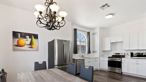 Una cocina moderna con armarios blancos, electrodomésticos de acero inoxidable y una mesa de comedor de madera.