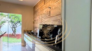 Une cuisine moderne avec un revêtement mural en bois, un four encastré et une porte en verre donnant sur un patio.