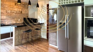 Une cuisine moderne avec un revêtement mural en bois, des appareils électroménagers en acier inoxydable et des luminaires suspendus.