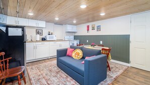 A compact kitchen with white cabinets, a black refrigerator, and a dining area with a table and chairs.