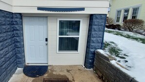 A house with a white door, a window, and a stone wall.