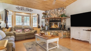 Una sala acogedora con chimenea de piedra, un sofá, una mesa de centro y un televisor.