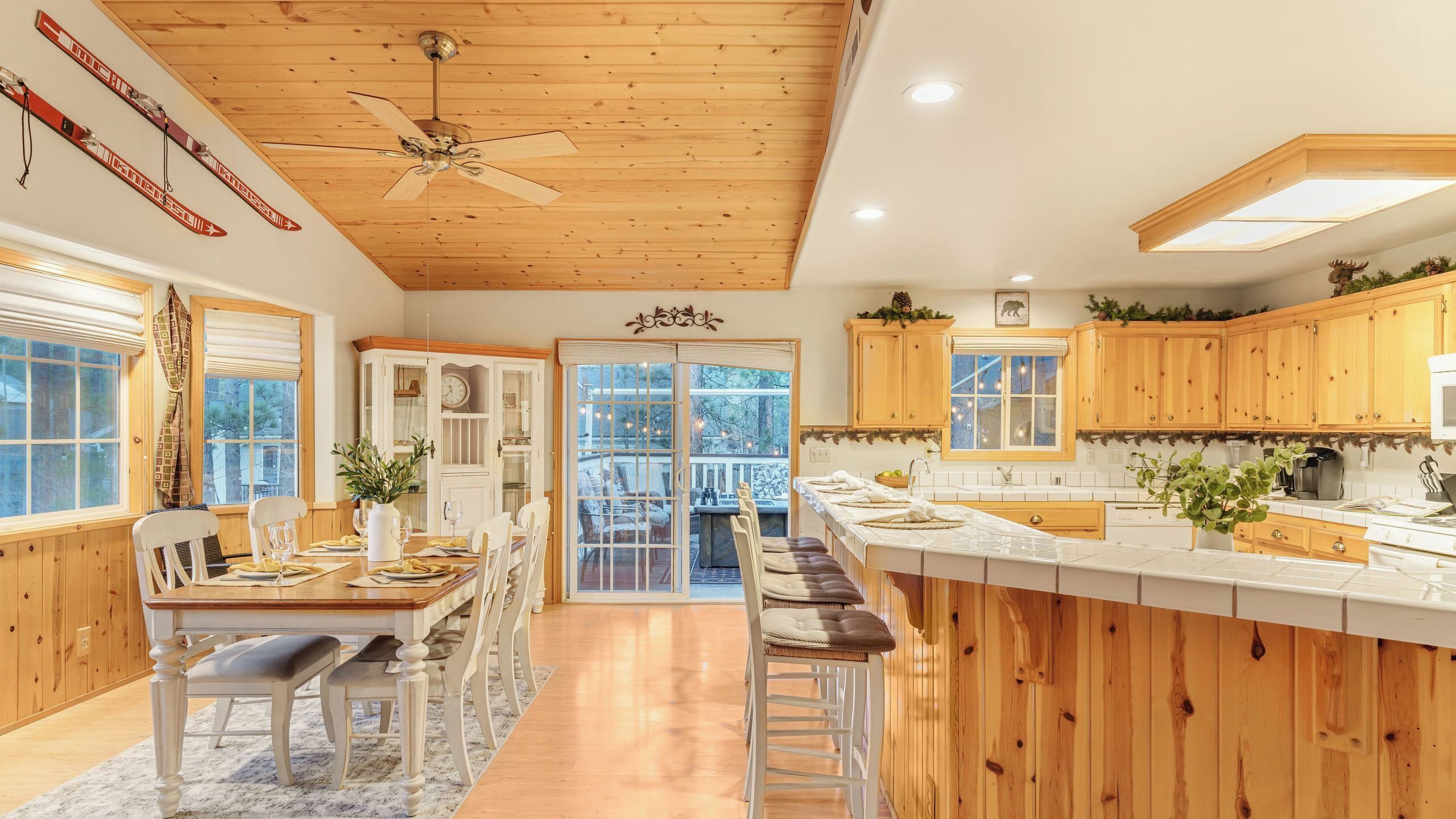 A kitchen with wooden cabinets, a ceiling fan, and a dining area with a table and chairs.