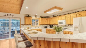 Una cocina con armarios de madera, una encimera blanca y una isla grande con taburetes de bar.