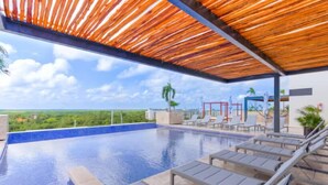 Ein Pool ohne Ende mit Liegestühlen, einer Holzpergola und Blick auf die Landschaft.