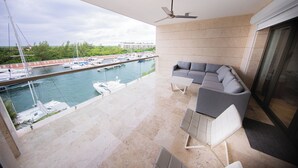 Ein Balkon mit Blick auf eine Marina, einer Couch und einem Deckenventilator.