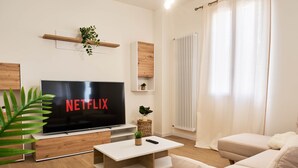 A modern living room with a flat-screen TV, a sofa, a coffee table, and a plant. - Ortensie House (Padua)