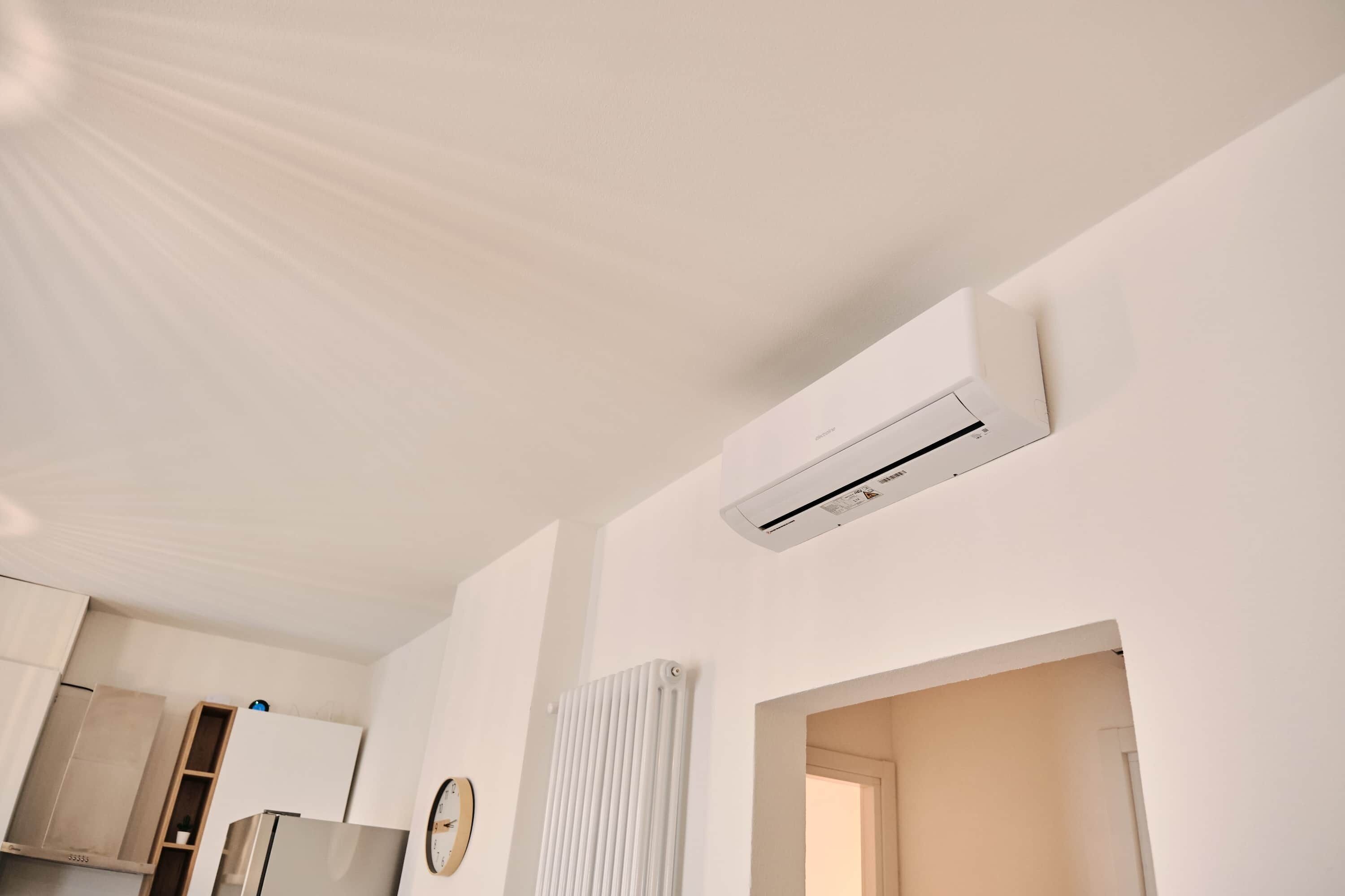 Eine moderne Küche mit weißen Schränken, einem Einbaukühlschrank, einer Klimaanlage und einer Heizung.