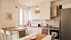 A modern kitchen with white cabinets, a wooden island, a hanging light fixture, and a stainless steel refrigerator. - Ortensie House (Padua)