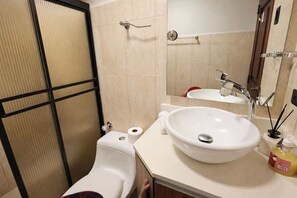 A bathroom with a toilet, bidet, sink, mirror, and towel rack.