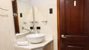 A bathroom with a white sink, a mirror, a toilet, and a wooden door. - Suite at Lomas de Urdesa walk to Tennis Federation (Guayaquil)