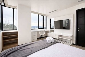 Ein modernes Schlafzimmer mit Bett, Fernseher, Schreibtisch und Stuhl.